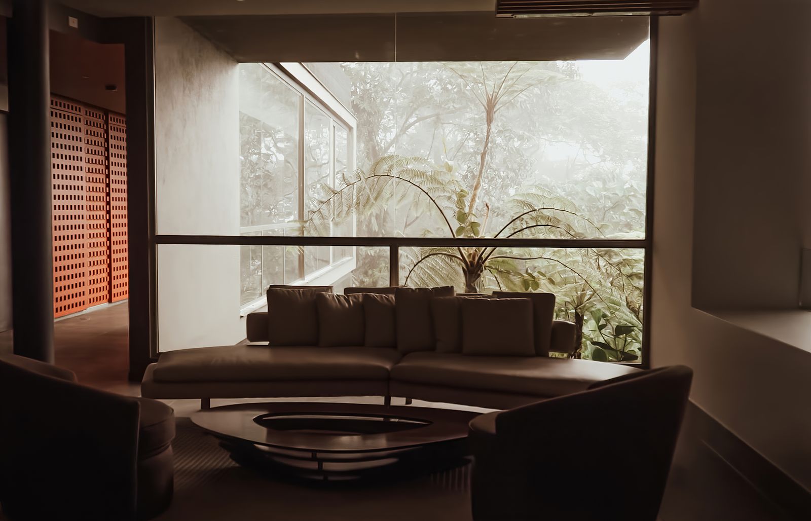 Large windows overlooking greenery in a warm, modern living room